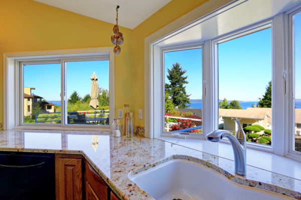 Kitchen cabinet with granite tops and sink with steel faucet. Kitchen has beautiful window view.